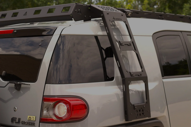 Close-up of the AEGON aluminum side ladder mounted on a Toyota FJ Cruiser below the roof rack
