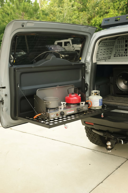 Aluminum drop down Molle table mounted on the rear door of a Toyota FJ Cruiser for organized cargo storage.