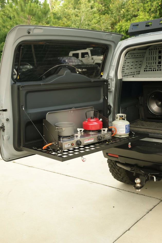 Aluminum drop down Molle table mounted on the rear door of a Toyota FJ Cruiser for organized cargo storage.