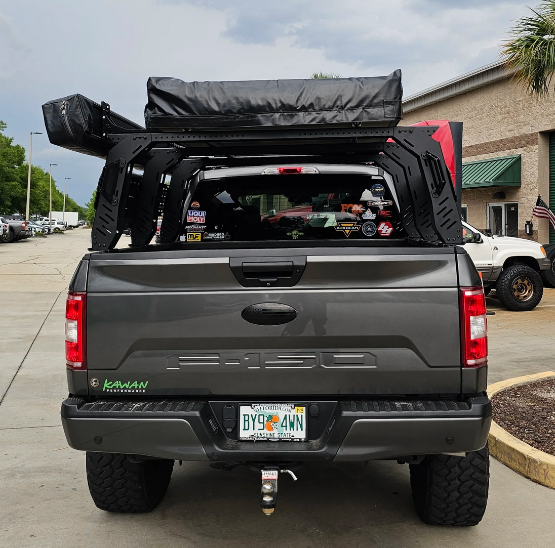 Aegon aluminum bed rack with integrated slots for mounting Rotopax fuel packs, recovery boards, and off-road tools.